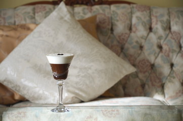 Espresso Martini cocktail, specialty alcoholic coffee drink in a crystal stem glass on a table by the couch. Relaxation at home.