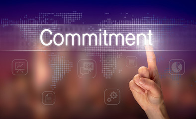 A hand selecting a Commitment business concept on a clear screen with a colorful blurred background.