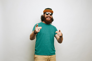 Cheerful happy bearded hipster man pointing at camera