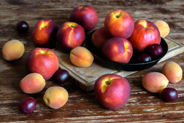 Ripe fruit nectarines, peaches, apricots on a wooden table. Summer still life in a rustic style.