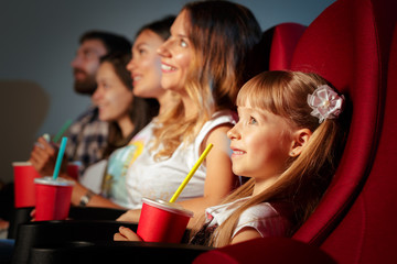 Group of friends sitting in movie theater with popcorn and drinks
