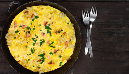 Traditional rustic omelette with bacon, pasta and greens