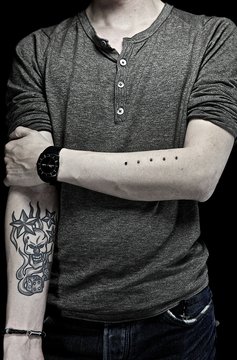 Tattoo and dermal anchors on the lower arms