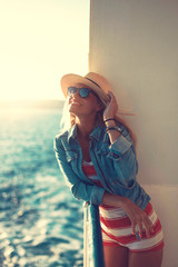 Happy blonde woman holding hat on cruise ship
