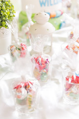 Glasses of Bagged Sweets on White Table with White Decorative Lamp.