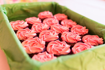 Obraz na płótnie Canvas Pink Sugar Coated Cup Cakes in Green Basket and Blurred Background