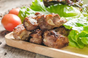 Close up fired pork rips on wooden plate with vegetable