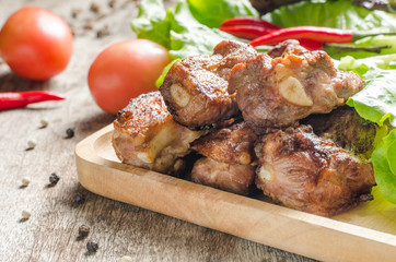 Close up fired pork rips on wooden plate with vegetable