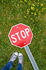 Feet selfie with stop sign on the green grass background