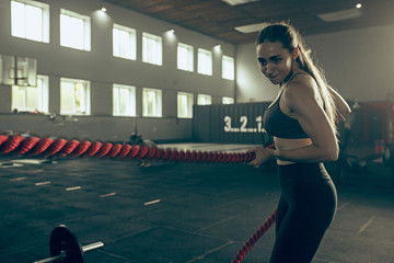 Fototapeta na wymiar Woman with battle ropes exercise in the fitness gym.