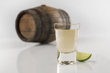 Authentic shot of Tequila with blurred barrel on background Mexican traditional drink accompanied...