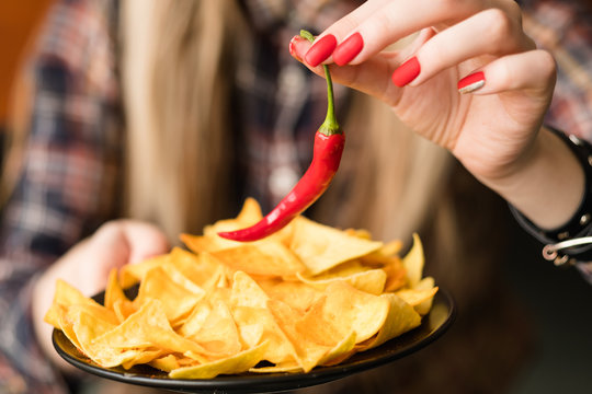 Hot Spicy Chips. Pungent Fiery Food Snack. Woman Hand Holding Nacho Crisps And Red Chili Pepper