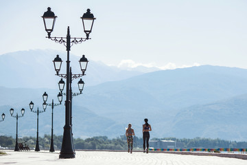 Girls doing sports, running in the morning along the promenade by the sea and mountains in the...
