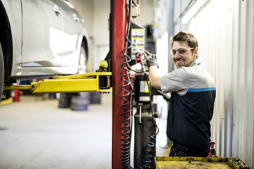 Fototapeta na wymiar Handsome mechanic job in uniform working on car