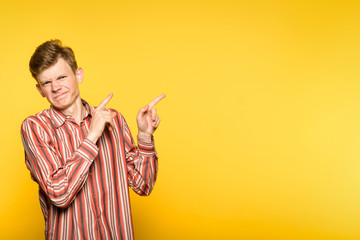 disapproving unapproving frowning critical man pointing sideways. portrait of a guy on yellow...