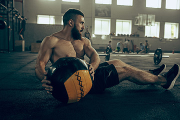 Fit young man lifting barbells working out in a gym
