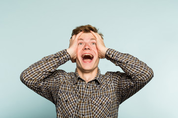 overjoyed extremely happy and excited man clutching his head. portrait of a young guy on light...