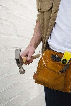 Male carpenter with tool belt holding hammer