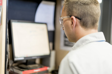 Professional car mechanic working in auto repair service using computer