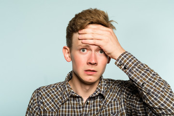 omg unbelievable shock amazement. dumbfounded man with open mouth clutching his head. portrait of a young guy on light background. emotion facial expression and reaction concept.