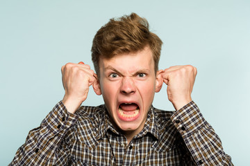 emotional breakdown. angry enraged infuriated crazy man screaming. portrait of a young guy on light...