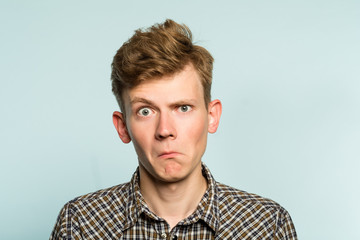 shocked perplexed puzzled bewildered man. portrait of a young guy on light background. emotion facial expression. feelings and people reaction.