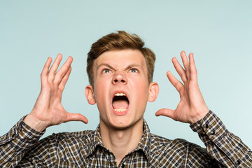 emotional breakdown. angry man in distress. agony and rage concept. portrait of a young guy on light background. emotion facial expression. feelings and people reaction.