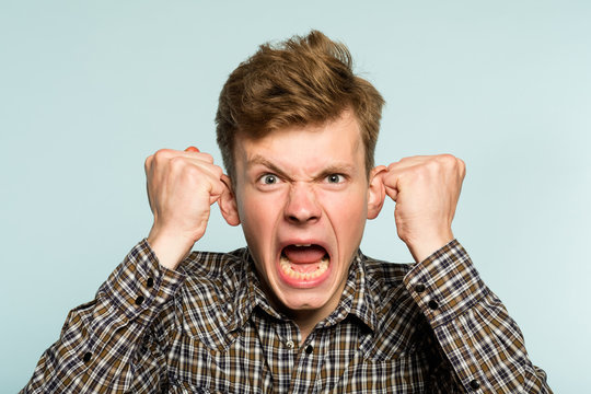 emotional breakdown. angry enraged infuriated crazy man screaming. portrait of a young guy on light background. emotion facial expression. feelings and people reaction.