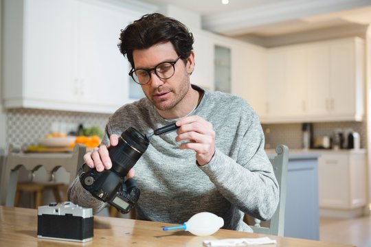 Man cleaning lens of digital camera at home