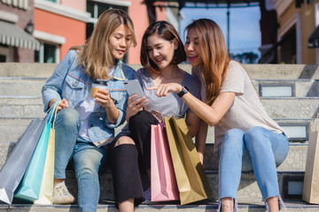 Attractive beautiful asian woman using a smartphone while shopping in the city. Happy young asian teenage at urban city while taking self portraits with her friends together with a smartphone.