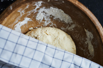 Top view of dough in a wooden bowl