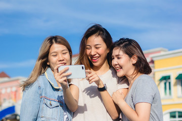 Fototapeta premium Attractive beautiful asian friends women using a smartphone. Happy young asian teenage at urban city while taking self portraits with her friends together with a smartphone.