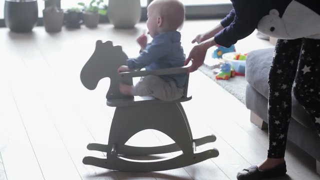 Boy toddler baby swinging on a rocking chair in the shape of a horse
