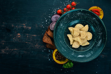 Dumplings with potatoes in a plate. Ukrainian Traditional Cuisine. On a wooden table. Top view. Copy space.