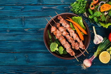 Baked Skewers of meat on a plate. On a wooden background. Top view. Copy space.