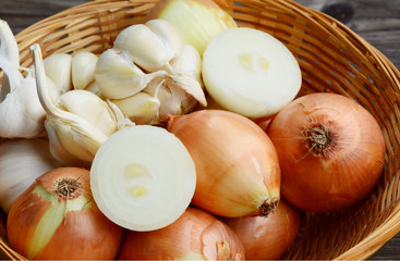 Yellow onions and Garlic are Vegetables or herbs Must be in the kitchen all the time.
Mixed onions and garlic in basket on wooden background.