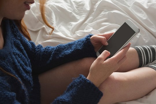 Woman using mobile phone in bedroom