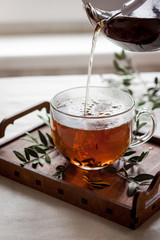 Cup of fresh herbal tea on wooden tray. The frozen movement. Selective focus.