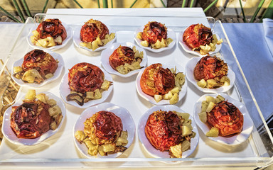 Tray with portions of rice-stuffed tomatoes and roast potatoes - selective focus