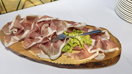 Wooden chopping board with large slices of ham