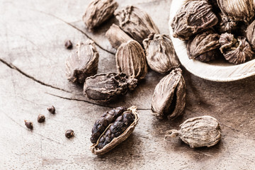 Spilled whole black cardamom on wooden background