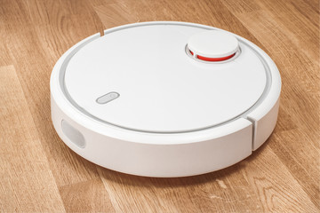 Robotic vacuum cleaner runs on laminate floor. modern smart cleaning technology housekeeping