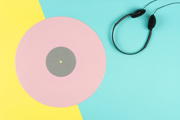 top view of a pink long play vinyl record or LP with a black on-ear headphone on the yellow and...