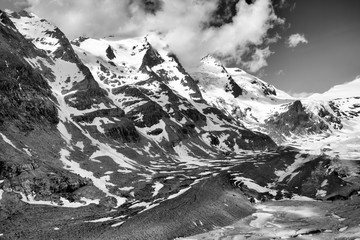 Dramatic view on the Grossglockner, seen from the Kaiser-Franz-Josefs-Höhe in the national wildpark in Tyrol, Austria. Partially snow covered mountains, shot against a partially clouded sky. 