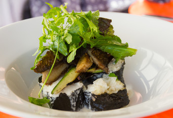 Rice rolls with mushrooms, lettuce and cucumber pieces on top in white big plate. Delicious vegetarian dish. Healthy eating concept