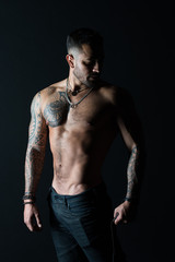 Fototapeta na wymiar Bodycare with fitness and sport. Man with tattooed arm and chest. Bearded man with strong torso. Tattoo model with sexy belly. Sportsman or athlete in fashion jeans