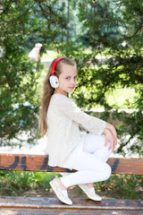 Naklejka premium Music sound and mp3. Little girl listen music in summer park. Child enjoy music in headphones outdoor. Fashion kid and modern technology. Summer vacation and fun