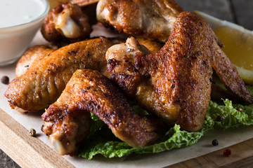 Close-up photo of bbq chicken wings with fries and beer. Barbeques meat with sauces, ketchup, mayonnaise. Fast and junk food concept. 