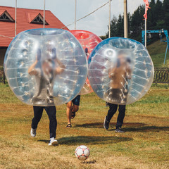 People play bumperball zorbsoccer outdoor. summer time