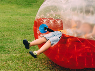 People play bumperball zorbsoccer outdoor. summer time
